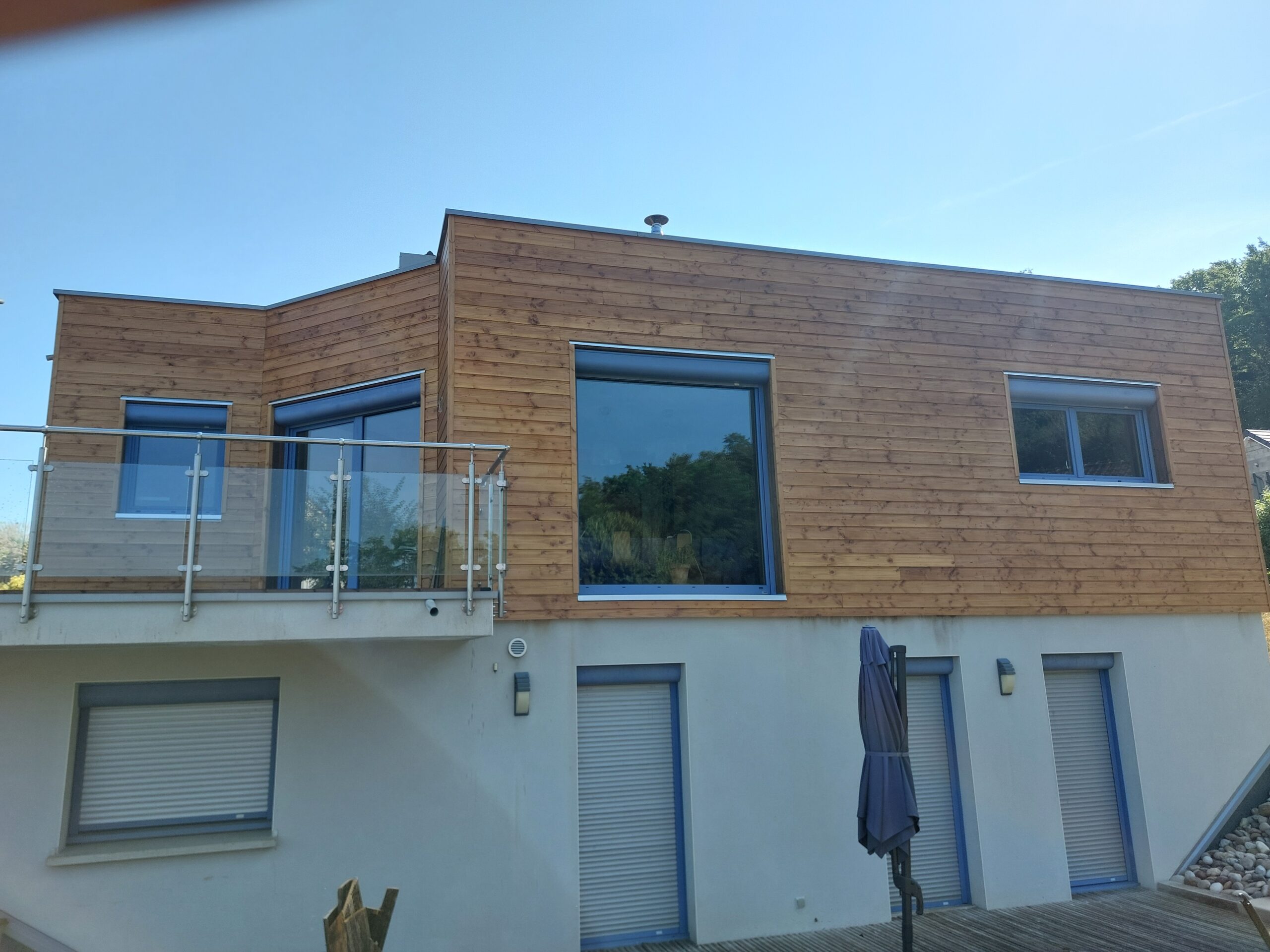 Rénovation terminée d'une maison moderne avec nouveau bardage bois Douglas à la teinte chaleureuse.