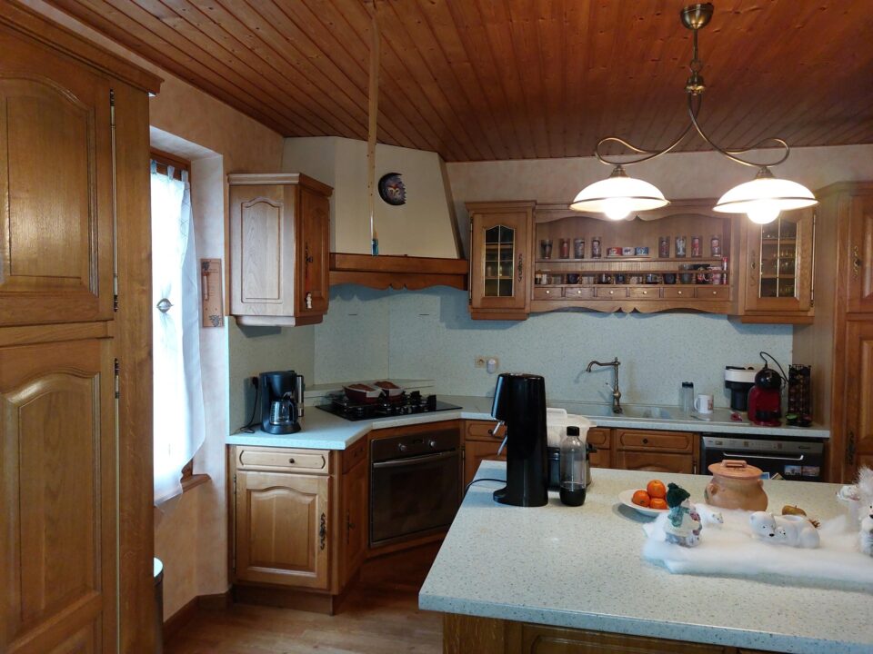 Ancienne cuisine rustique en bois sombre à Suarce avant la rénovation partielle.
